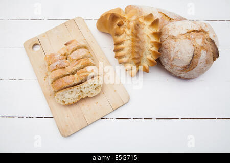 Loafs and slices of bread on a white wood table Stock Photo