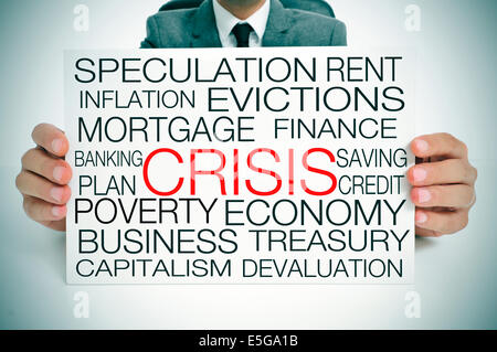 a businessman holding a signboard with different terms related to the economic crisis concept Stock Photo
