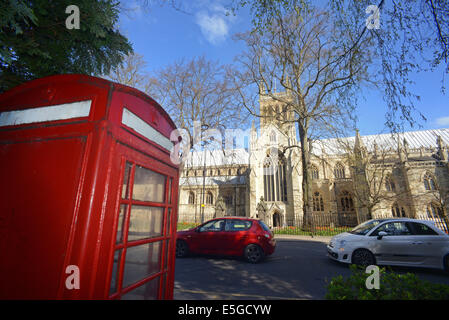 cars passing red telephone box by selby abbey at springtime founded in 1069 by benedict of Auxerre north yorkshire uk Stock Photo