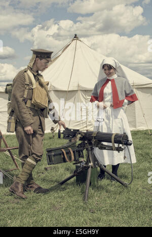 Great War QAINS Reserve Staff Nurse (grey cape) with uniformed British Army Machine Gunner showing her a Vickers Machine Gun Stock Photo