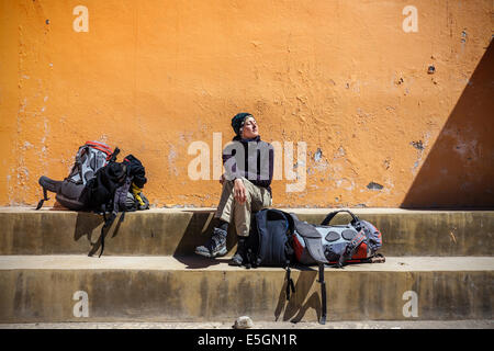 Girl waiting with backpacks in sun. Stock Photo