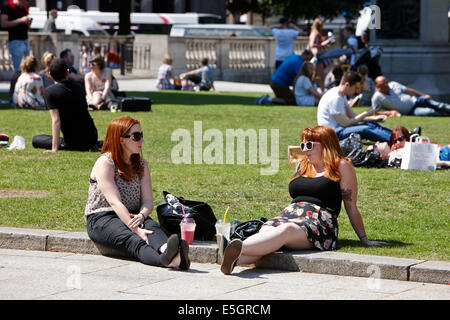 two red headed women enjoying cool drink on hot summers day in the grounds of Belfast city hall in the city centre Stock Photo