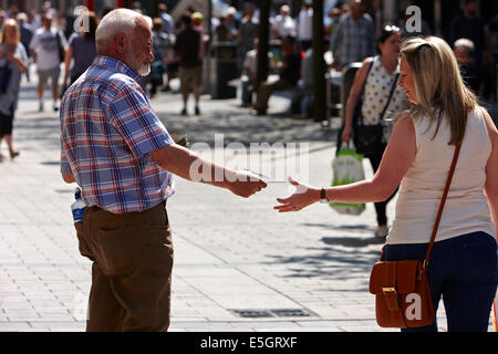 religious preacher handing out leaflets to woman in Belfast city centre northern ireland Stock Photo