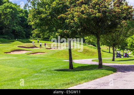 Four male golfers playing near bunkers on a golf course. Stock Photo