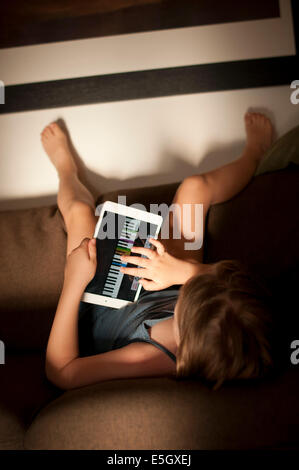 Six year old girl using an ipad mini tablet computer at home. Stock Photo