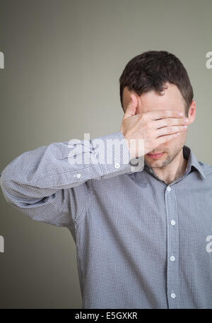 Young sad Caucasian man hiding his face with hand Stock Photo