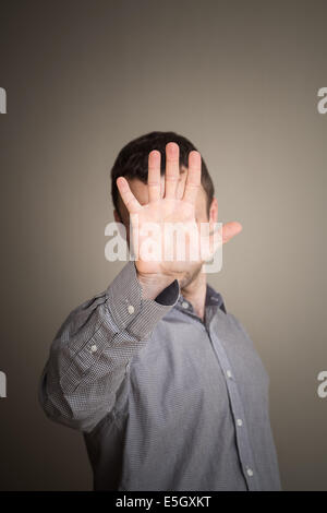 Young Caucasian man hiding his face with hand Stock Photo