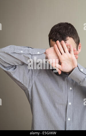 Young Caucasian man hiding his face with hands Stock Photo