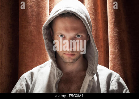Portrait of young Caucasian man in the hood with red curtain background Stock Photo