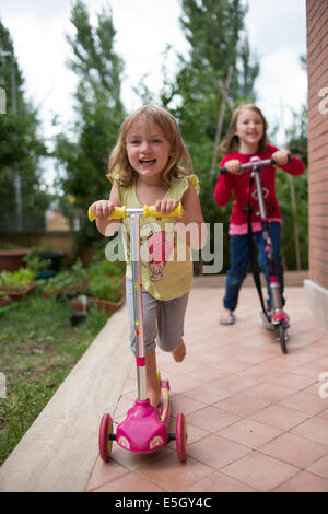 Two young girls riding micro scooters. Stock Photo