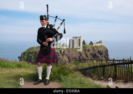 Piper playing bagpipes in traditional Scottish kilt at Dunnottar Castle near Stonehaven in Aberdeenshire Scotland UK Stock Photo