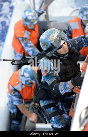 A Chinese sailor with a boarding team assigned to the guided missile destroyer Haikou (DD 171) climbs a ladder to board the nat Stock Photo