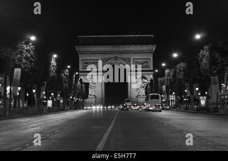 Arc de Triomphe lit up at night on Avenue des Champs Elysees Paris in a black and white photo Stock Photo