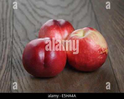 three nectarines on old wood oak table, rustic style Stock Photo