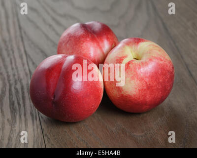 three nectarines on old wood oak table, rustic style Stock Photo