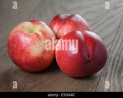 three nectarines on old wood oak table, rustic style Stock Photo