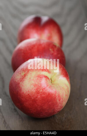 three nectarines on old wood oak table, rustic style Stock Photo