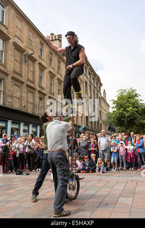 Street entertainer performing with a unicycle and using two members of the audience to help, Buchanan Street, Glasgow, Scotland, Stock Photo