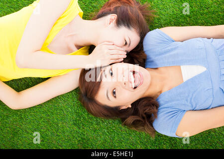 two sisters  whispering gossip on the grass Stock Photo