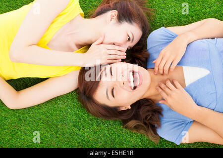 sisters whispering on the meadow and happy expression Stock Photo