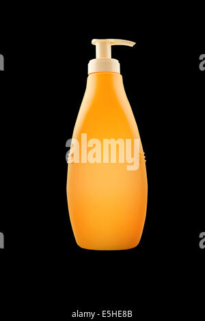 Nourishing body milk bottle with work path. Blank yellow plastic bottle isolated on black background. Stock Photo