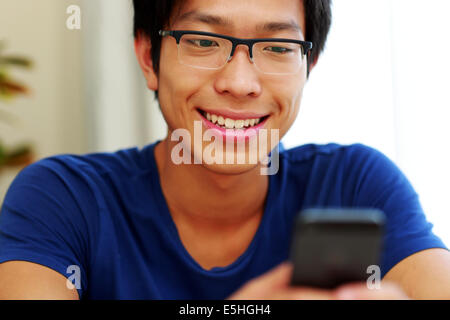 Happy asian man using smartphone at home Stock Photo