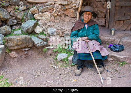 Mature Quechua Indian woman wearing a hat sitting on a stone in front of a doorway, Cordillera Huayhuash, Northern Peru, Peru Stock Photo