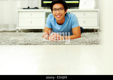Happy asian man lying on the floor at home Stock Photo