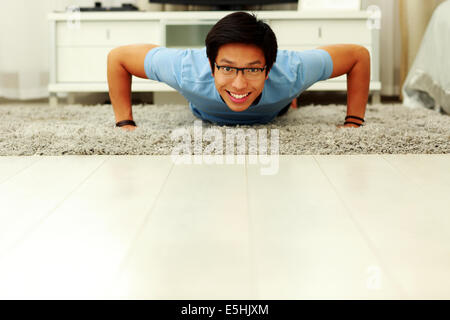 Portrait of a sporty young man doing push ups in the living room at home Stock Photo