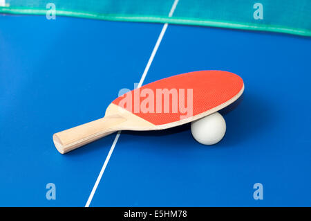 red table tennis bats on a blue table with green net in background Stock Photo