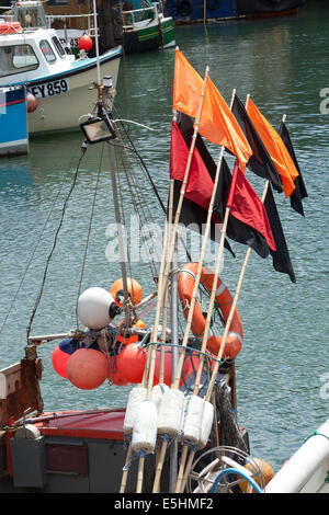 Flags used by fishing men to mark where lobster pots and nets are on the seabed, the harbour at Mevagissey, on the of Cornwall. Stock Photo