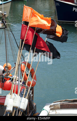 Flags used by fishing men to mark where lobster pots and nets are on the seabed, the harbour at Mevagissey, on the of Cornwall. Stock Photo