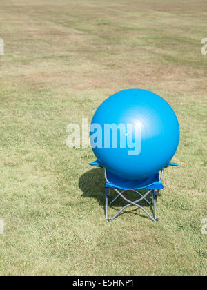 modern art, a blue ball on a blue chair in a field Stock Photo