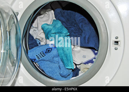 close up of an open door of a loaded washing machine with laundry Stock Photo
