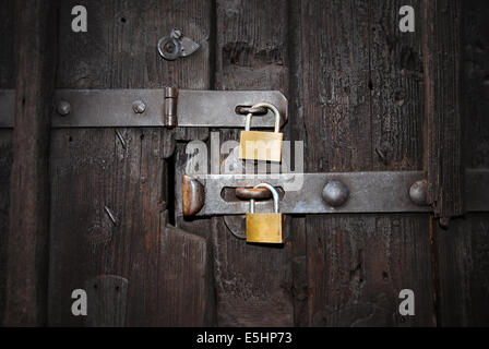 two golden safety locks with latch on an old, wooden door, close up Stock Photo