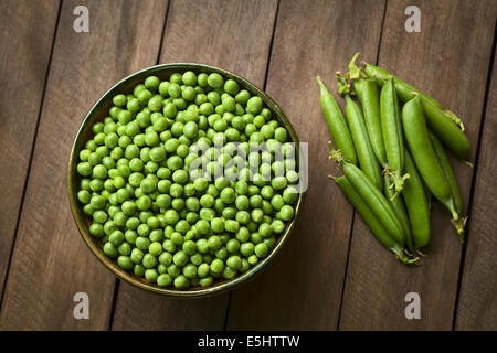 Peas (lat. Pisum sativum) in bowl with closed peapods on the side Stock Photo