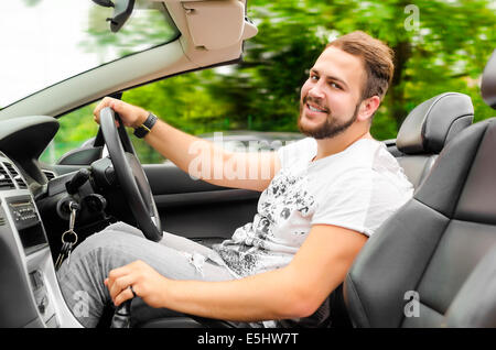Smiling handsome young man driving cabriolet outdoors Stock Photo