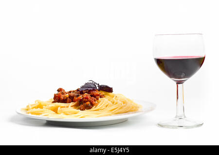 one serving of spaghetti bolognese with a glass of red wine shot from a low angle