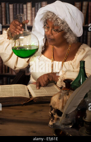 Old time alchemist working in her laboratory with green poison in a flask Stock Photo