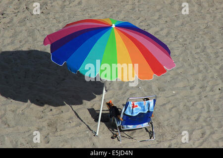 A colorful beach umbrella and chair on the sand of a beach on the Atlantic Ocean in Hollywood Beach, Florida, USA Stock Photo