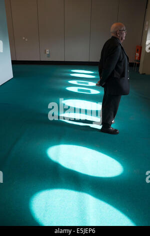 Man Standing in Pool of Sunlight Streaming Through Windows Stock Photo