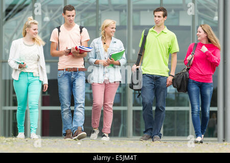 Five students are walking with their school supplies in their hands Stock Photo