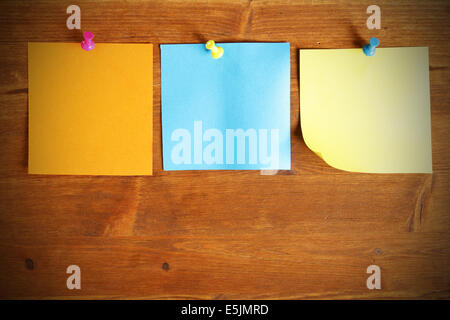Three colorful blank note papers attached to a wooden wall Stock Photo
