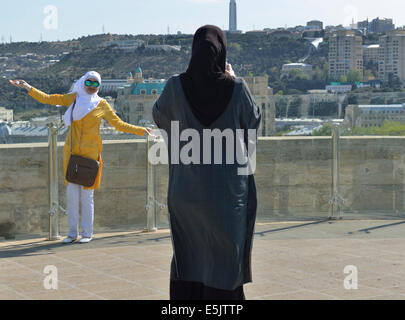 Two women taking photos on viewing platform of the Maiden Tower, Old City, Baku, Azerbaijan Stock Photo