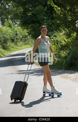 Young woman on roller skates with a rollalong case Stock Photo