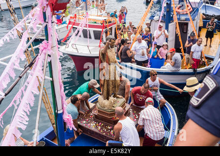 San Juan, Tenerife, Canary Islands, Spain. 03rd Aug, 2014. The Nuestra senora del Carmen and San Juan Bautista effigies are taken to the harbour and loaded on to fishing boats for a maritime procession accompanied by an armada of boats to visit neighboring fishing villages as part of the annual fiesta in Playa San Juan, tenerife, canary Islands, Spain. Credit:  Phil Crean A/Alamy Live News Stock Photo