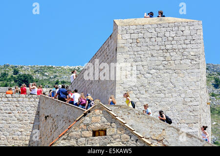 Young group of tourists walking up steps on Dubrovnik city walls on a hot blue sky summer day (possibly a school trip) Croatia Dalmatia Adriatic Sea Stock Photo