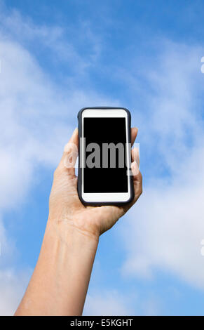 Generic cell phone held by female hand against blue sky with clouds. Stock Photo