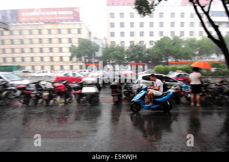 Taiyuan, China's Shanxi Province. 4th Aug, 2014. A citizen rides a motorcycle on a road in Taiyuan, capital of north China's Shanxi Province, Aug. 4, 2014. Heavy rainfall hit the city on Monday. Credit:  Fan Minda/Xinhua/Alamy Live News Stock Photo