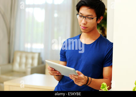 Serious asian man using tablet computer at home Stock Photo